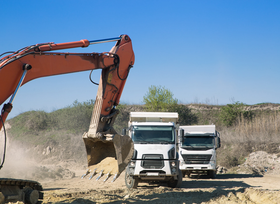 Excavadora junto a dos camiones
